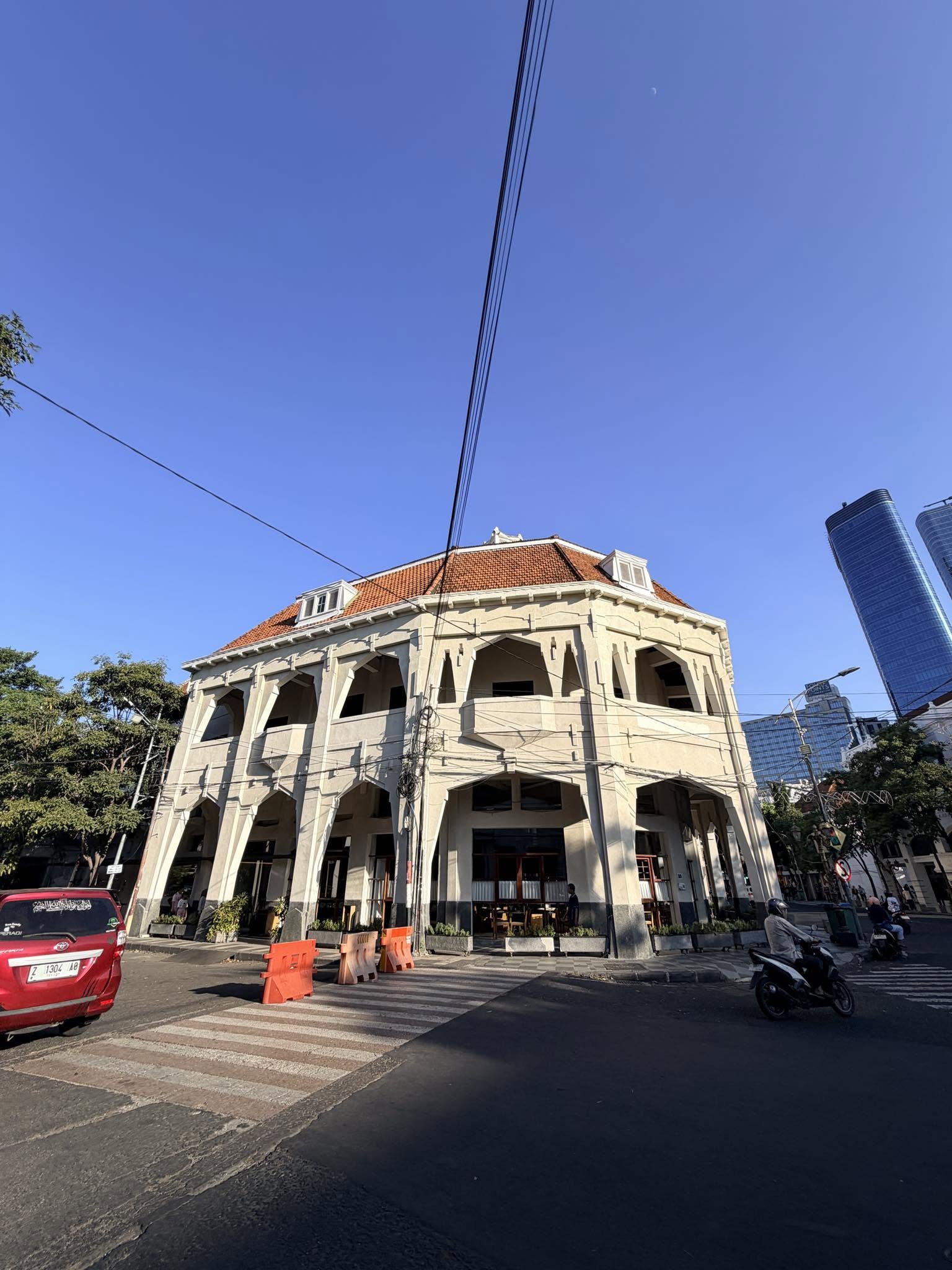 泗水 Tunjungan 39 拱廊外觀與後方藍色玻璃摩天樓對比